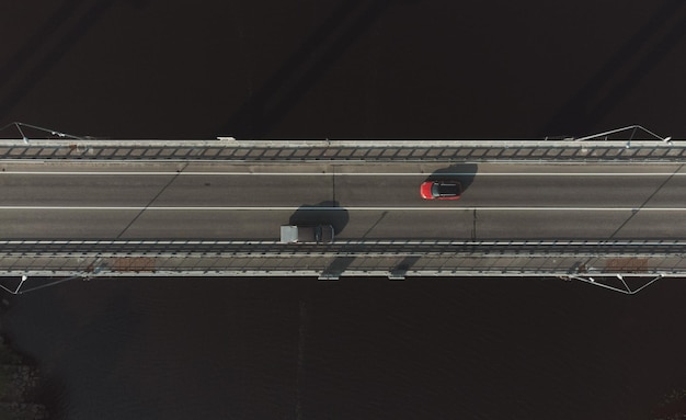 Twee auto's rijden in verschillende richtingen op de wegbrug over de rivier Bovenaanzicht