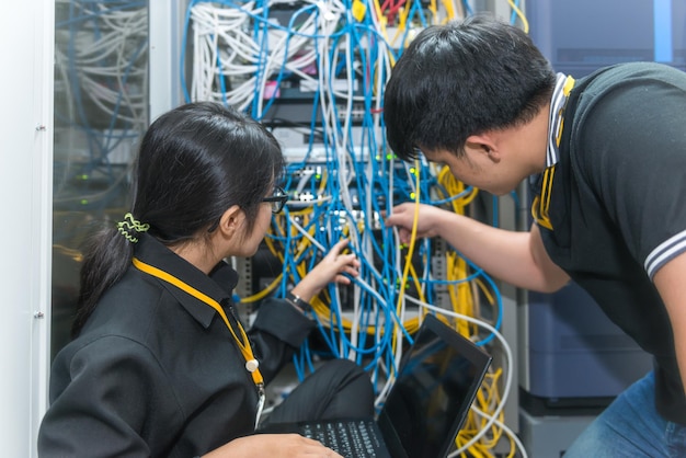 Twee Aziatische ingenieurs die in de serverruimte werkenControleer de verbindingsproblemen van computernetwerkenThailand mensen