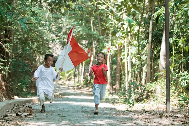 Twee Aziatische jongens rennen met de rood-witte vlag vast en hijsen de vlag