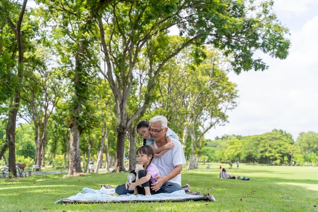 Twee Aziatische kleindochters met opa en oma zitten en praten op het gras buiten in het park overdag Het leeftijdsverschil is veel warme liefde