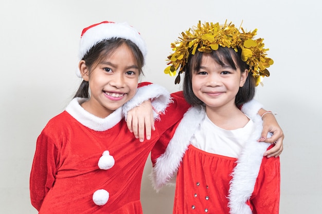 Twee Aziatische kleine kindermeisjes die een rood kerstmanpak dragen om kerstvakantie thuis te vieren