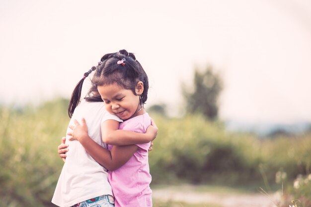 Twee Aziatische meisjes die elkaar met liefde in uitstekende kleurentoon koesteren