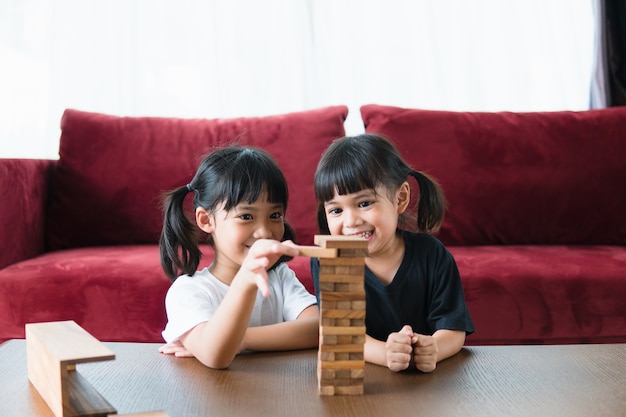 Twee Aziatische meisjes die thuis houten stapels spelen