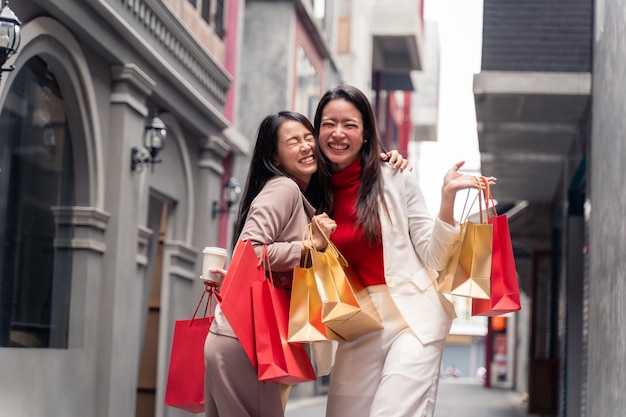 Twee Aziatische mooie vrouwen met boodschappentassen in de stad over winkelcentrum achtergrond