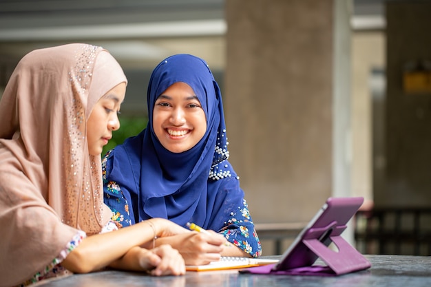 Twee aziatische musalim werken en bespreken met tablet op kantoor.