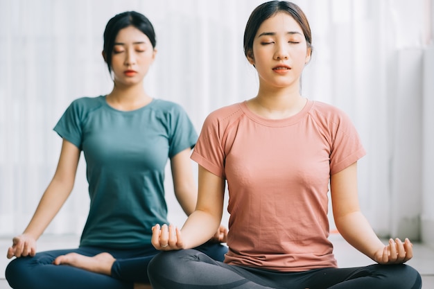 Twee Aziatische vrouwen beoefenen thuis meditatie