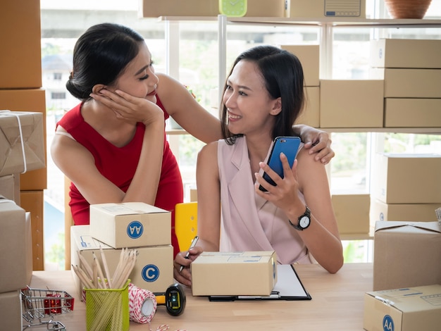 Twee Aziatische vrouwen met het start kleine bedrijfs freelance ondernemer thuis werken. het controleren van de productbestelling.