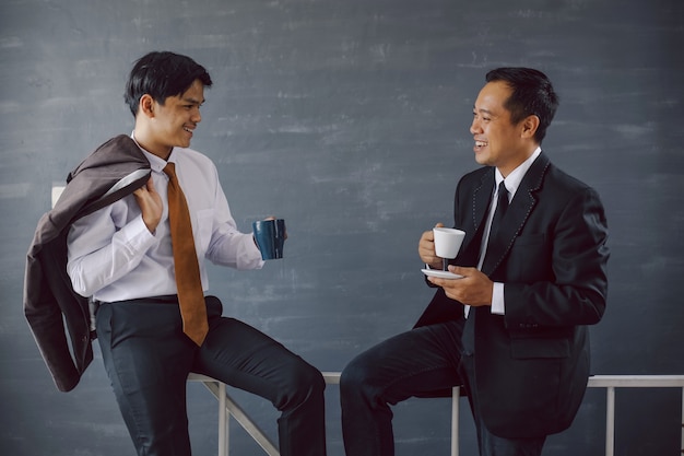 Twee Aziatische zakenlieden kletsen terwijl ze koffie houden tijdens een pauze