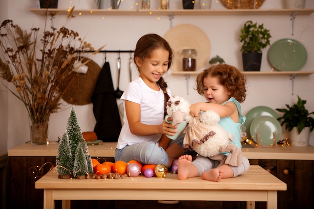 twee baby meisjes mandarijnen eten in de keuken van Kerstmis