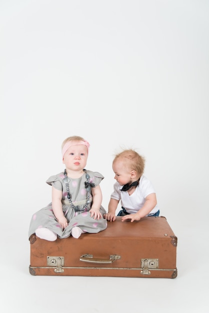 Twee baby's met de koffer op de witte ruimte