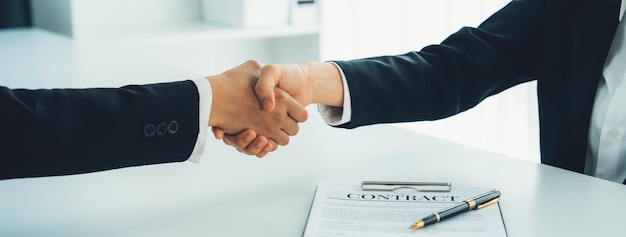 Twee bedrijfsleiders schudden de hand in de raad van bestuur om de fusieovereenkomst te verzegelen. De handdruk symboliseert zakelijk partnerschap en samenwerking.