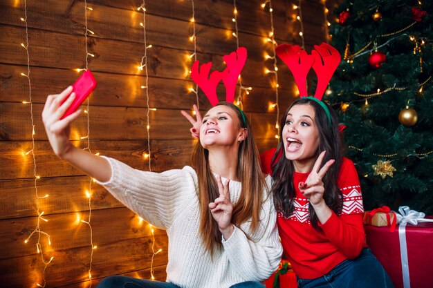 Twee beste vrienden die selfie in slaapkamer dichtbij Kerstboom nemen