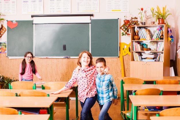 Twee beste vrienden knuffelen en lachen in de klas