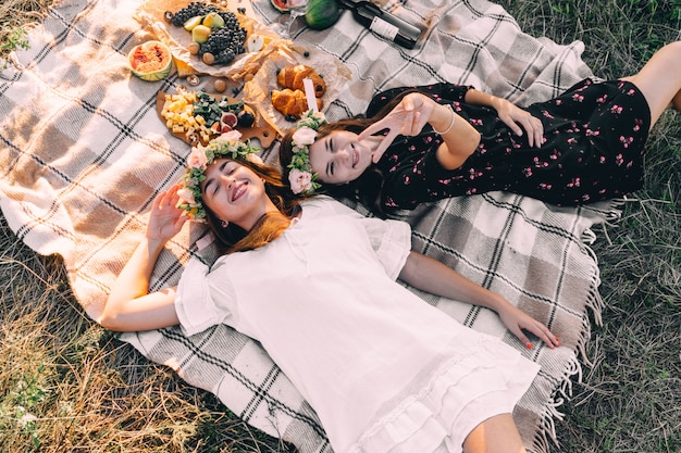 Twee beste vrienden op picknick in het gebied die op de gelegde het glimlachen hoogste meningsvriendschap leggen