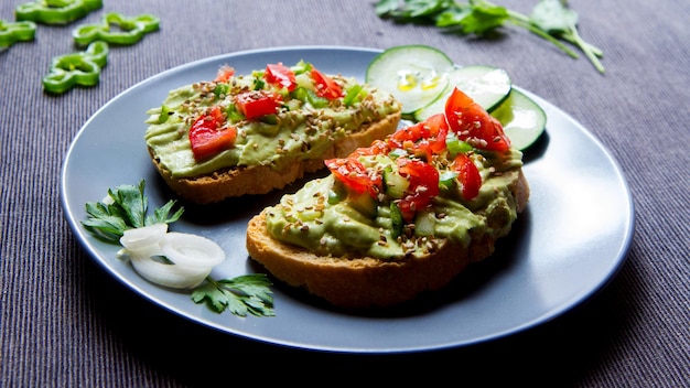 Twee biologische broodtoosts met avocado en cherrytomaatjes