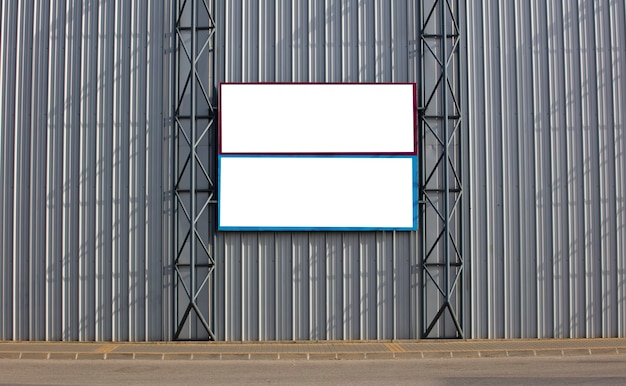 Twee blanco posters geplakt op een metalen muur buiten de gebouwen