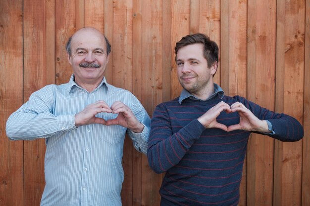 Foto twee blanke mannen die een handhart maken