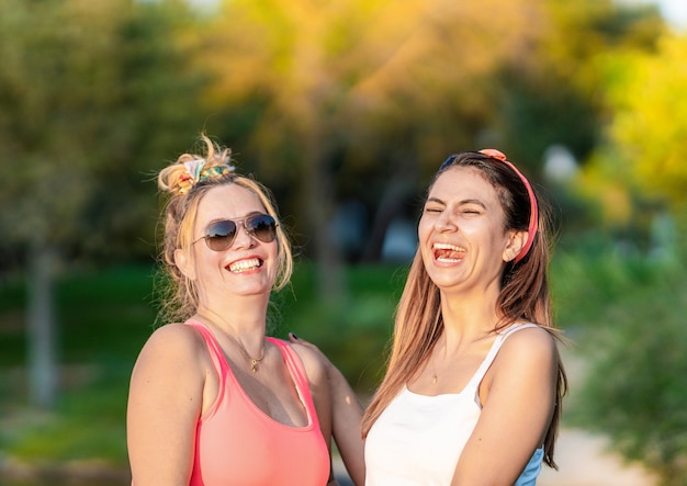 Twee blanke vrouw die lacht terwijl ze in een park staat