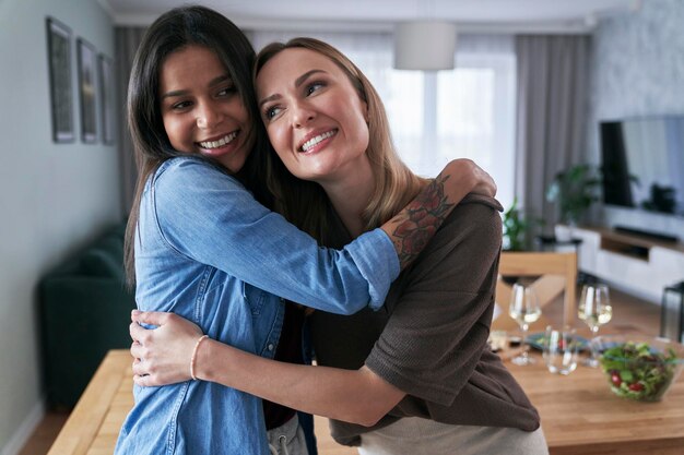 Twee blanke vrouwen omhelzen elkaar thuis.