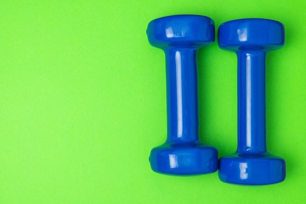 Twee blauwe dumbbells geïsoleerd op groene achtergrond