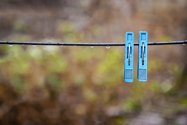 Foto twee blauwe wasknijpers op een natte touw