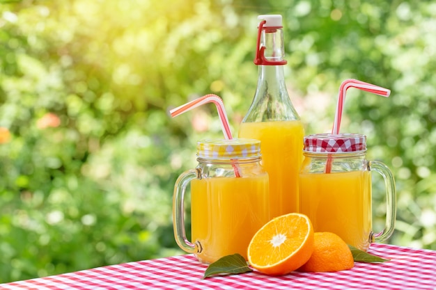 Twee blikken en fles met jus d'orange op rood geruit tafelkleed