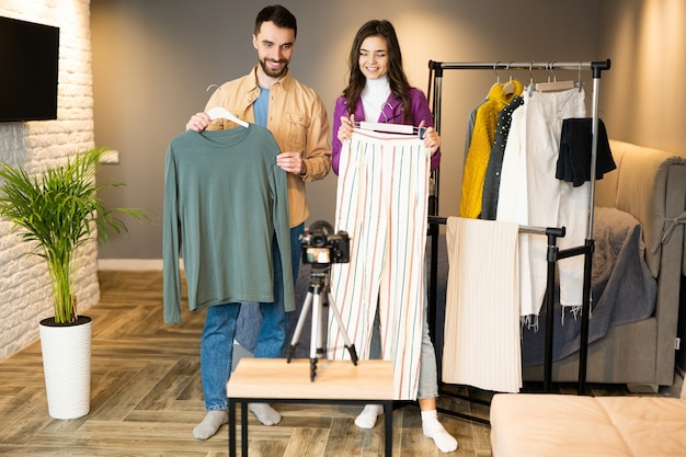 Twee bloggers-influencers maken reclame voor kleding voor online winkels. Mooi meisje en jongen filmen een vlog over kleding