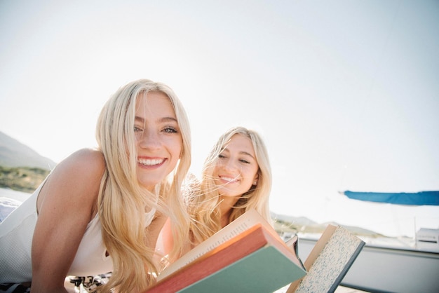 Twee blonde zusjes liggen op een steiger een boek te lezen