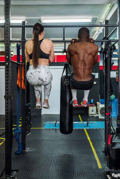 Twee bodybuilders, een zwarte en een blanke, doen in een sportschool een halteroefening. Concept van het versterken van het lichaam in de sportschool