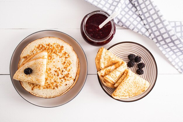 Twee borden pannenkoeken met bramen en een pot jam Top view Traditioneel eten voor de vakantie van afscheid van de winter in Rusland