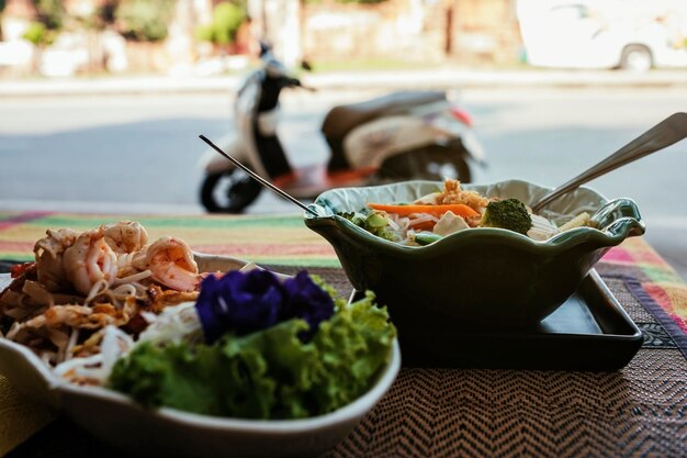 Twee borden pittig Thais eten op de veranda op straat Op de achtergrond motorfiets