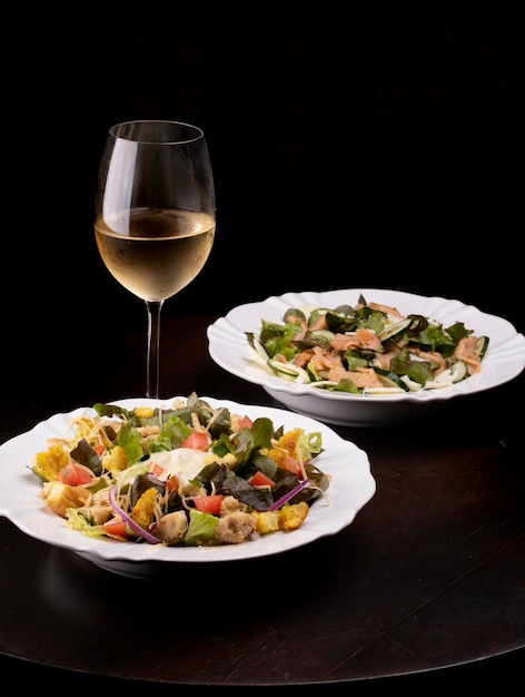 Twee borden salade en een glas witte wijn op houten tafel gezond eten portret