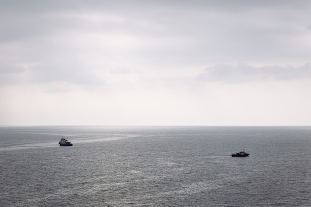 Twee boten varen in verschillende richtingen op de zee op een bewolkte dag