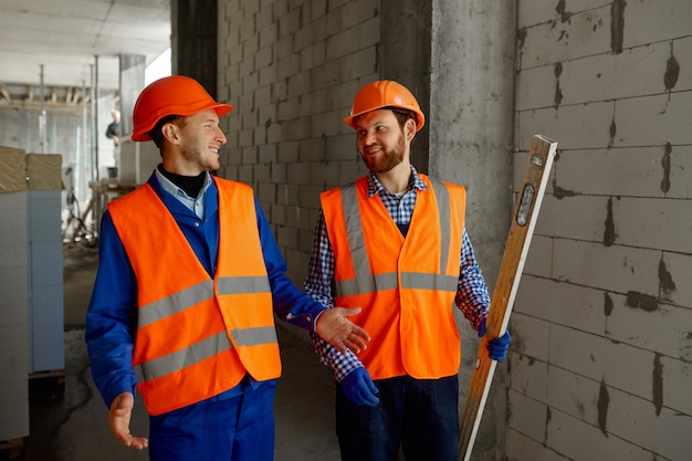 Twee bouwers in uniform lopen en praten over de bouw