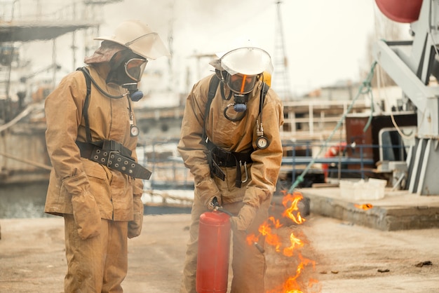 Twee brandweerlieden in maskers en apparatuur op een training hoe het vuur te doven