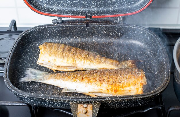 Twee branzino-vissen gekookt in een zwarte grillpan