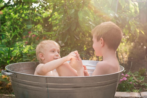 Twee broers die baden in een metalen bassin in het dorp lachen en hebben plezier, rust op het platteland