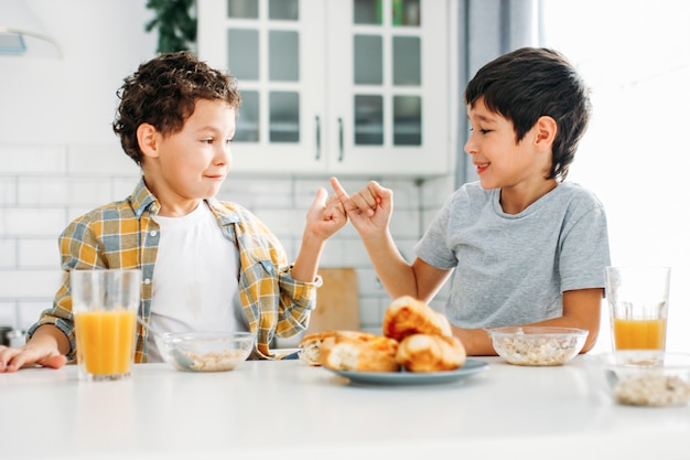 Twee broers en zussen tween jongens echte broers thuis ontbijten op lichte keuken