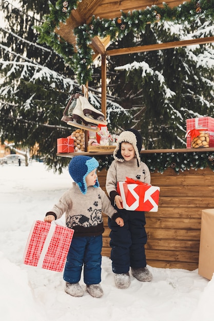 Twee broers jongens met geschenkdozen op kerstmarkt Candy Shop buiten