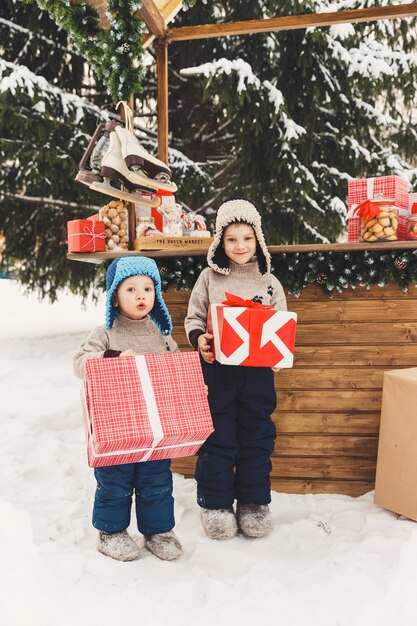 Twee broers jongens met geschenkdozen op kerstmarkt Candy Shop buiten