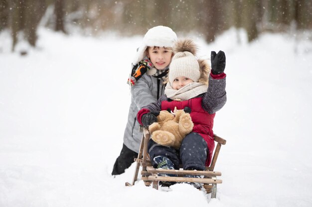 Twee broers rijden op een vintage houten slee tegen de achtergrond van een winterbos