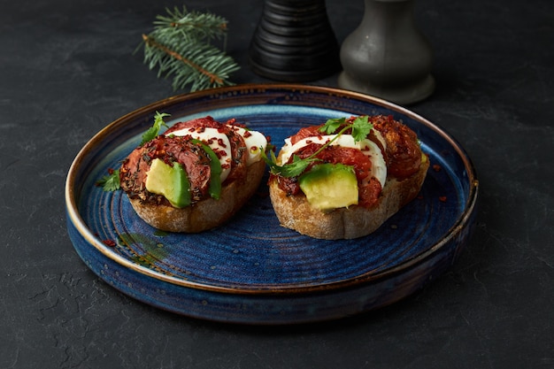 Twee brusquetten met avocadovlees en kaas liggen op een bord