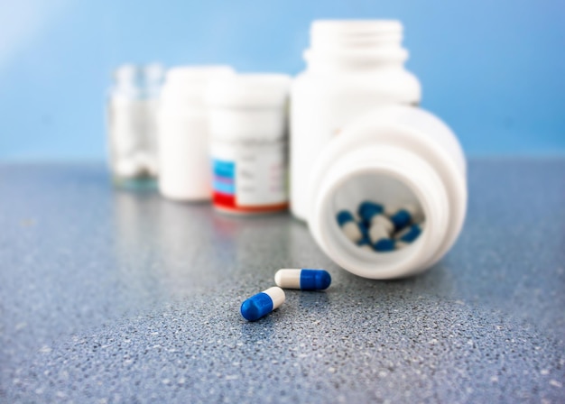 Twee capsules en verpakkingen met medicijnen op een onscherpe achtergrond in de verte Het concept van capsules met tabletten en dozen met potten met medicijnen