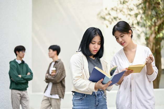 Twee charmante aziatische vrouwelijke studenten bespreken en zoeken informatie in een boek