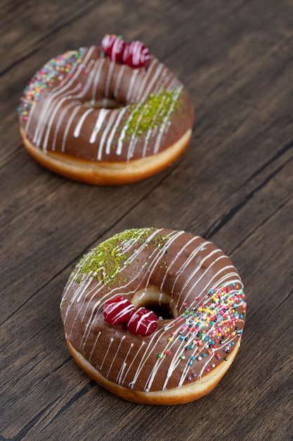 Twee chocolade donuts met hagelslag op een houten tafel.