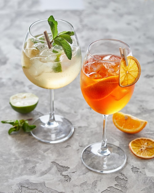 Twee cocktails met limoen en ijs over grijze achtergrond