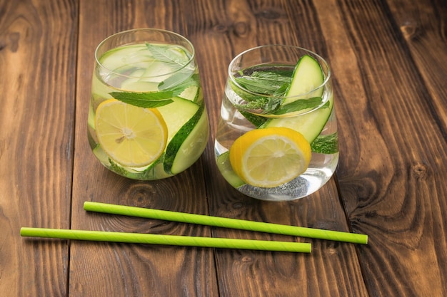 Twee cocktailtubes en twee glazen met een drankje van citroenmunt en komkommer