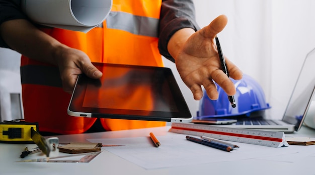 Twee collega's bespreken gegevens over werken en tablet-laptop met op architecturaal project op de bouwplaats aan de balie op kantoor