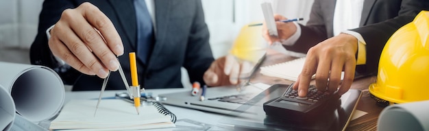 Twee collega's bespreken gegevens over werken en tablet-laptop met op architecturaal project op de bouwplaats aan de balie op kantoor