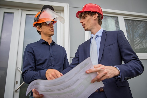 Twee collega's bespreken het gebruik van een plattegrond ingenieurs op het werk